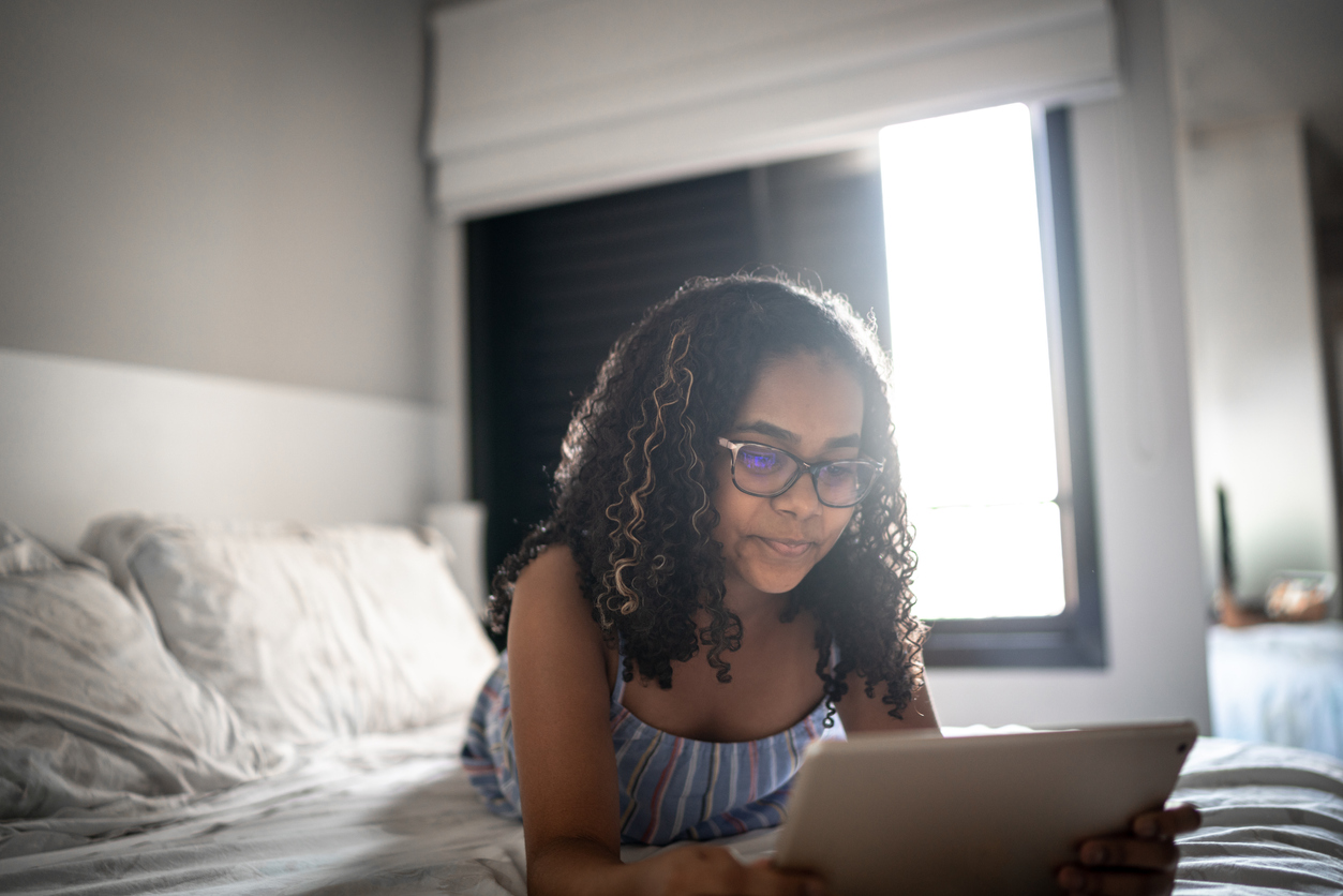 Adolescente lendo tablet em casa.