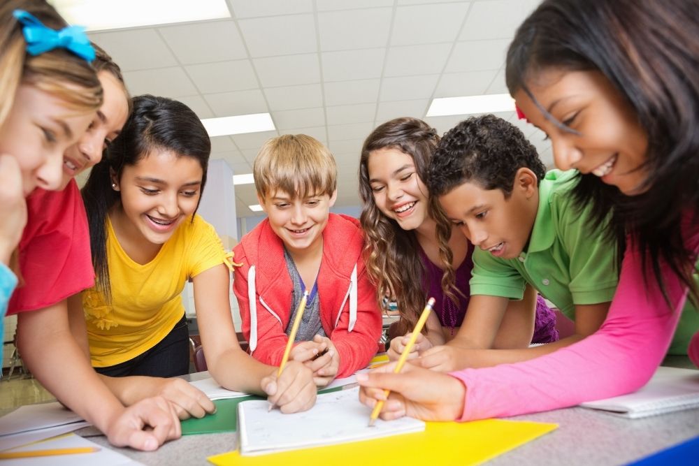 estudantes colaborando em um trabalho em grupo em uma sala de aula.