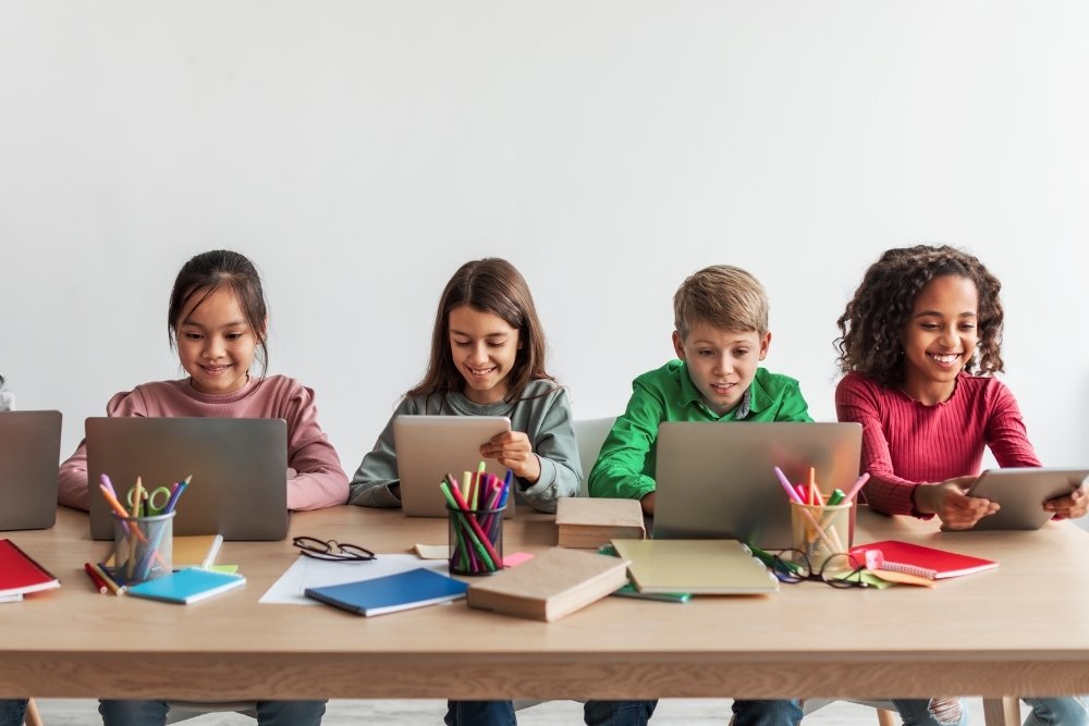 grupo de alunos usando tablets e notebooks durante atividade digital.