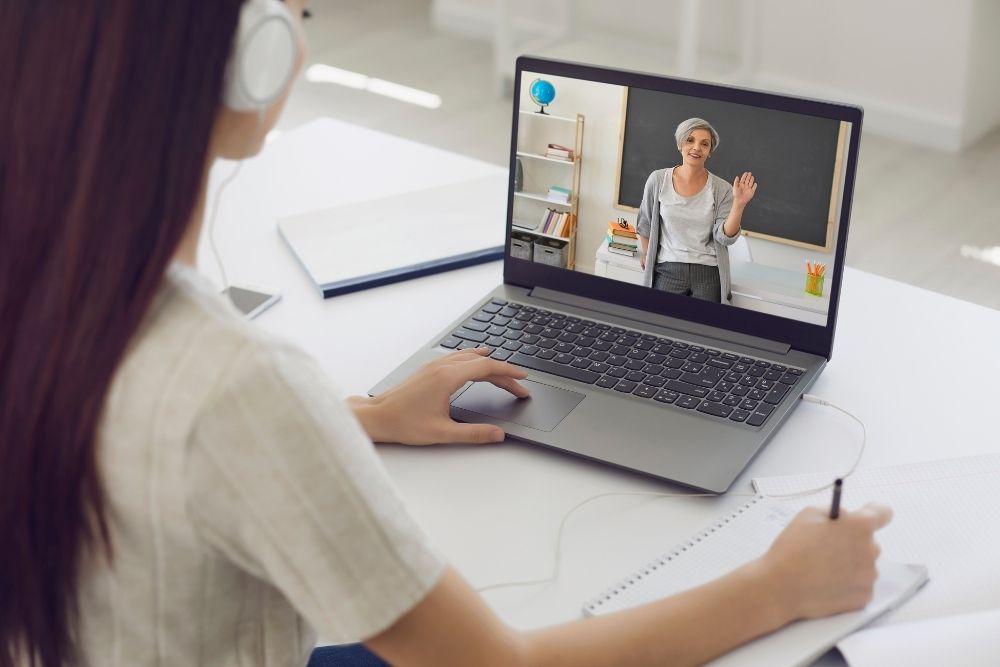 aluna assiste aula online com professora em plataforma educacional.