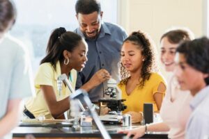 professor auxiliando alunos em um experimento de ciências em laboratório.