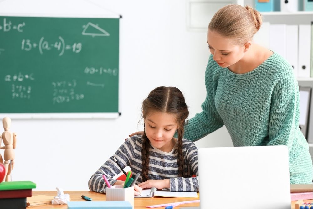 orientadora educacional auxiliando aluna em uma atividade escolar.